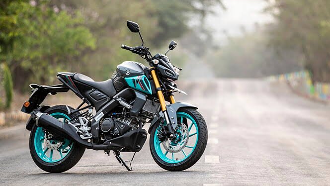 "Yamaha MT 15: A sleek black motorcycle cruising down an open road with mountains in the background."